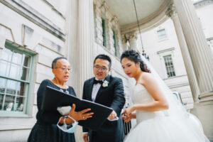 Wedding officiant, Leora Lewis in DC Potomac with a newly married couple looking down at a book together.