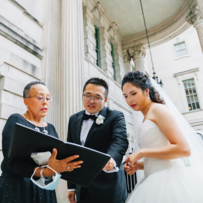 Wedding officiant, Leora Lewis in DC Potomac with a newly married couple looking down at a book together.